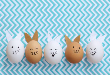 Çizgili mavi chevron arka plan üzerinde kahverengi ve beyaz Paskalya bunny yumurta