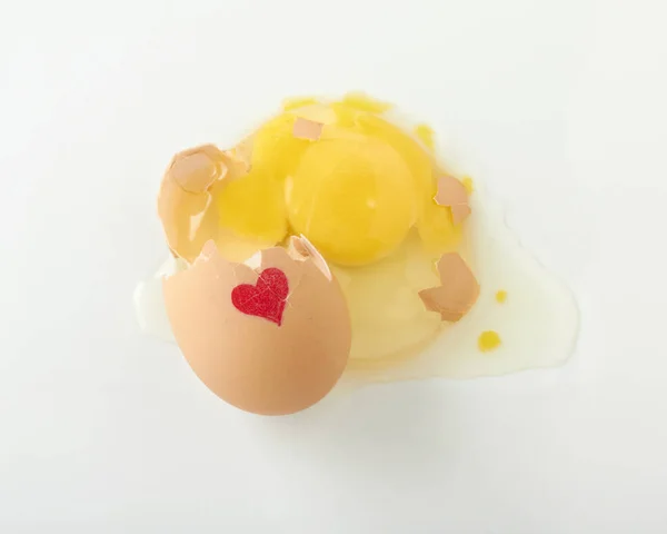 Egy repedt nyers tojást, egy piros szív fehér felületre Jogdíjmentes Stock Fotók