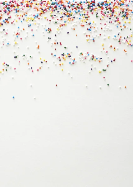 Background of rainbow nonpareil sprinkles on a cream surface Royalty Free Stock Images