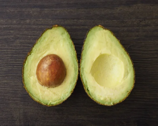 Две половинки разрезанного авокадо на деревянной поверхности — стоковое фото