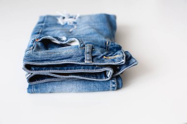 Katlanmış mavi kot beyaz arka planda yatıyor.