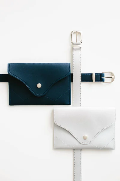 Blue and metal waist bags on a white background