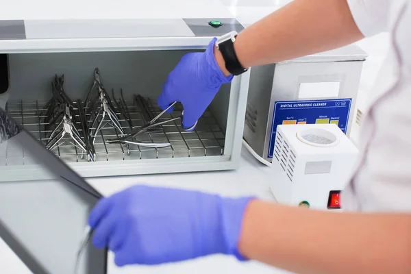Uzman, ultraviyole sterilizatörden manikür aletleri çıkarıyor.