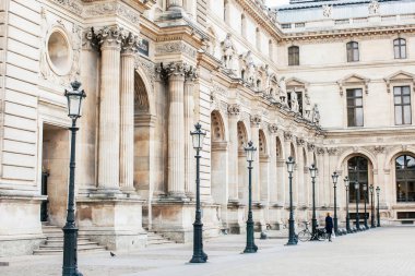 Paris 'in bir caddesinde siyahlı yalnız bir kadın. COVID sırasında Fransa - 19 salgın. Louvre Müzesi.