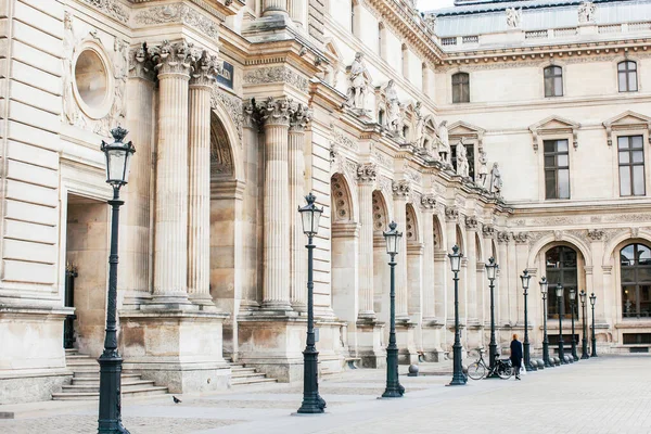 Paris 'in bir caddesinde siyahlı yalnız bir kadın. COVID sırasında Fransa - 19 salgın. Louvre Müzesi.