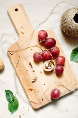 Şarap, kırmızı üzüm ve ceviz için aperatifler tahtanın üzerinde gelişigüzel durur. Durgun hayat.