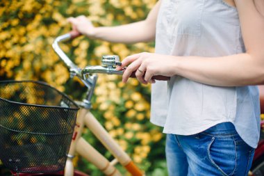 Kız bisikletin direksiyonunu tutuyor, yakın plan. Doğada yaz yürüyüşü.
