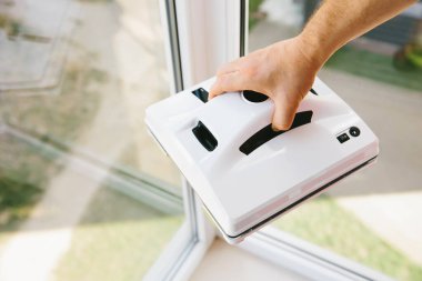 Adam bardakları yıkamak için robot elektrikli süpürge tutuyor. Ev asistanı kavramı.