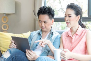 Genç çiftler modern yaşam tarzı kavramı için çağdaş evin oturma odasında birlikte tablet kullanıyorlar.