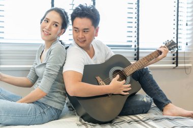 Genç çift gitar tohether modern yaşam konsepti için çağdaş evin yatak odasında oynarken