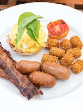 Yumurtalı nefis kahvaltı. Benedict, pastırma, sosis ve patates püresi.