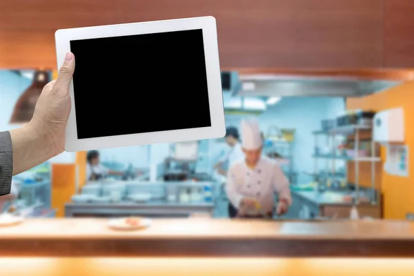 商業キッチンぼやけて シェフの手で背景を料理デジタル タブレットを保持します — ストック写真