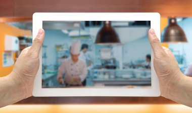 Dijital tablet ticari mutfak bulanık ve arka plan üzerinde yemek Şef ile el ele tutuşur