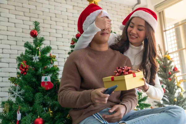 美しいアジアの女の子はクリスマス休暇の季節の挨拶で彼女のボーイフレンドに驚きのクリスマスプレゼントを与える — ストック写真