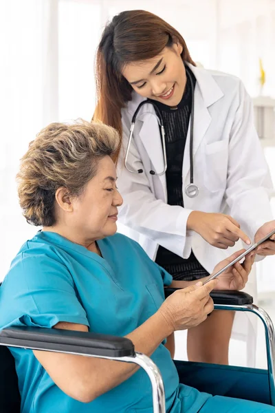 亚洲自信医生使用数码平板电脑对坐在轮椅上的老年妇女表达健康问题 — 图库照片