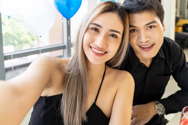 若いアジアの大人のカップルは 大都市の大きなアパートのリビングルームで一緒に新年とクリスマスの休日を祝うために自撮り写真を作る — ストック写真