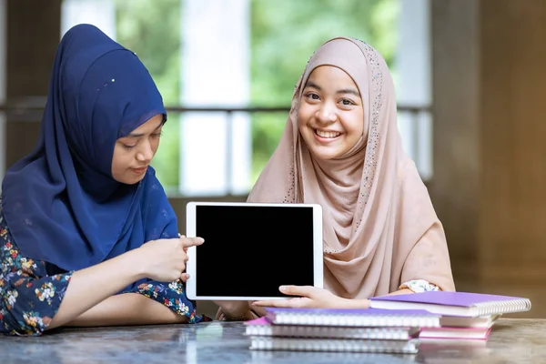 ティーネージャー ヤング アダルト アジアタイ ムスリム大学の学生は 教育やオンライン教育の概念を使用してデジタルタブレットや書籍の山を保持 — ストック写真