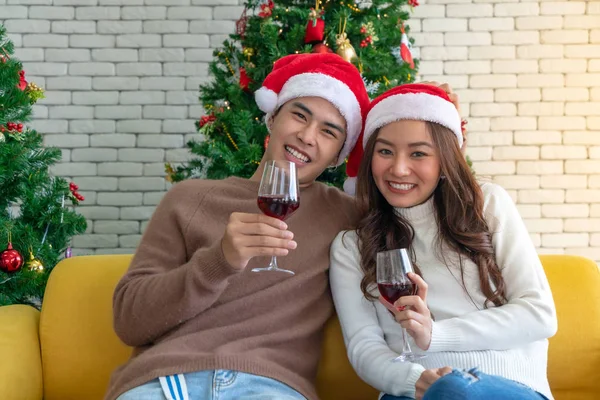 若いですアジアの大人のティーンカップルお祝いクリスマス休暇でワインと一緒にリビングルームでクリスマスツリーの装飾 — ストック写真
