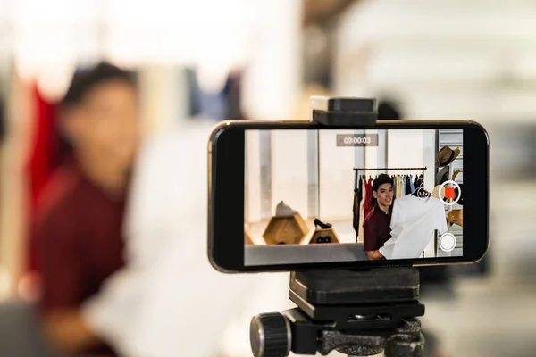 年轻的亚洲男性在线商人时尚博主使用智能手机录制直播Vlog视频来评论休闲装 社交媒体概念的在线影响力 以手机为重点 — 图库照片