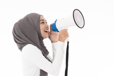 Başörtüsü takan genç Müslüman kadın, pazarlama ya da satış fikri için megafonla yüksek sesle bağırarak iletişim kuruyor. Stüdyo çekimi beyaz arkaplanda izole edildi.