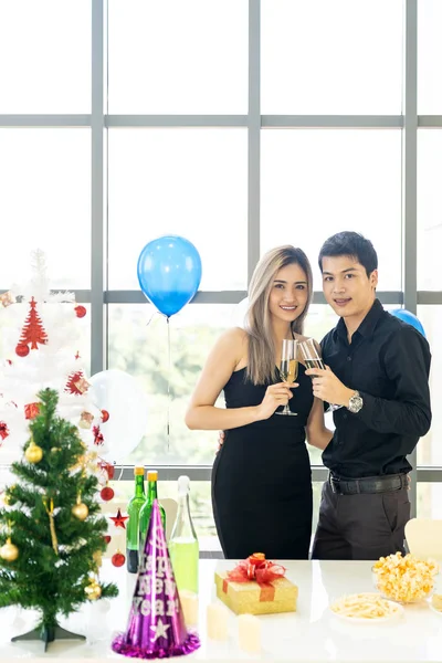 大都市の大きなマンションのリビングルームで一緒に輝くワインと一緒に新年のクリスマスの休日を祝う若いアジアの大人のカップル — ストック写真