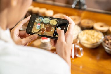 Genç Asyalı girişimci blogcusu sosyal medya için kafe kahve dükkanını gözden geçiriyor ve kafede online pazarlama yapıyor. Küçük işletme oluşturma ve tüketim kavramının başlangıcı için kullanılacak. 