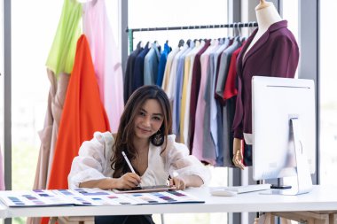 Genç yetişkin moda tasarımcısı tek sahibi olarak renk paleti olan atölyesindeki dijital tabletini çiziyor ve çiziyor. Girişimci başlangıç konsepti için kullanılıyor.
