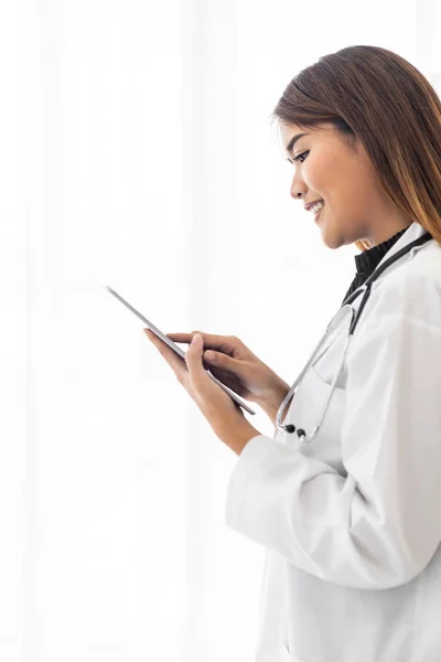 形象自信的女医生站在医院诊疗室使用数码平板电脑 正面的表情 — 图库照片