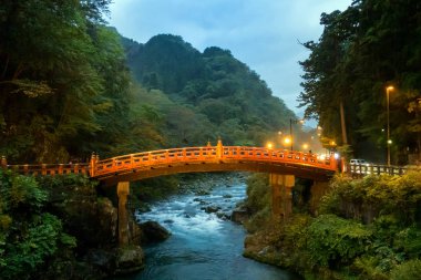 Nikko Tochigi Japonya 'daki nehir deresinin üzerindeki tarihi kırmızı köprü alacakaranlık günbatımında.