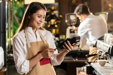 Asyalı Barista, bir kafe barda kahve almak için Emv çipi teknolojisini kullanarak müşteri kredi kartıyla ödeme yapıyor..