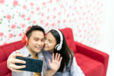 Evdeki kanepede oturan ve öpüşen evli çiftin videosu. Koca kameraya bakıp el sallıyor merhaba diyor ya da abone kanalına elveda diyor. Sosyal medya vlog yazıcı kavramı.