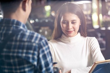 Asyalı kadın müşteri kredi kartı okuyucu Edc makinesinde cep telefonu scane Qr kodu kullanarak kafedeki kahve için garsona ödeme yapıyor..