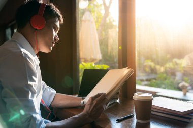 Odaklanmış Asyalı üniversite öğrencisi test veya sınava hazırlanan kafede dizüstü bilgisayarla çalışıyor..