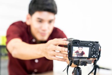 Genç Asyalı erkek blogcu evde video kaydı yapmak için kamera kuruyor. Bloglama veya vloglama, sosyal medya hobi yayıncılığı veya çevrimiçi öğrenim kursu kavramı.
