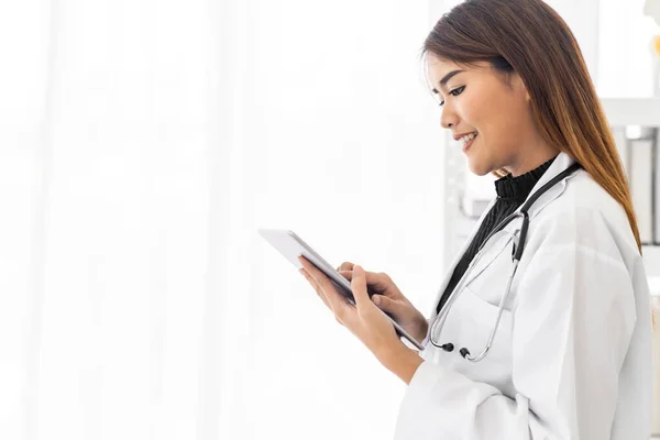 形象自信的女医生站在医院诊疗室使用数码平板电脑 正面的表情 — 图库照片