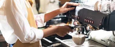 Modern kahve makinesinin kahve makinesiyle kahve yapan bir baristanın diğer baristalarla kahve yaparken yakın çekimi. Küçük işletme girişimcisi Panorama web pankartı sahibi için kullanılıyor.