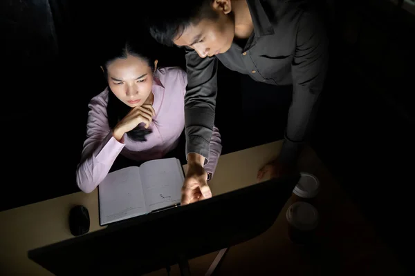 年轻的亚洲商人和同事们讨论深夜在办公室用台式计算机工作的问题 采用努力工作和工作到深夜的概念 — 图库照片