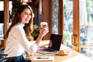 Karantina genç Asyalı kadın şık giyiniyor. Evde dizüstü bilgisayar kullanıyor, sıcak kahve içiyor ve kruvasan içiyor. Şehir covid-19 Corona virüsü salgını yüzünden tecrit altında..