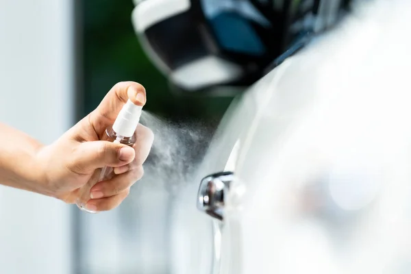 Closeup car wash cleaning using hand spraying alcohol, disinfectant spray on car door handle for safety prevent and protect from infection of virus and germ Covid-19 corona-virus world pandemic.