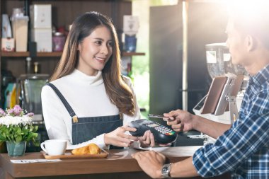 Temassız kredi kartı kullanan Asyalı müşteri Kafe Bar 'daki kahveciye ödeme yapıyor. Korona-virüsü covid-19 'un yayılmasını ve enfeksiyon kapmasını engelleyen temassız ödeme, Panoramik web pankartı.