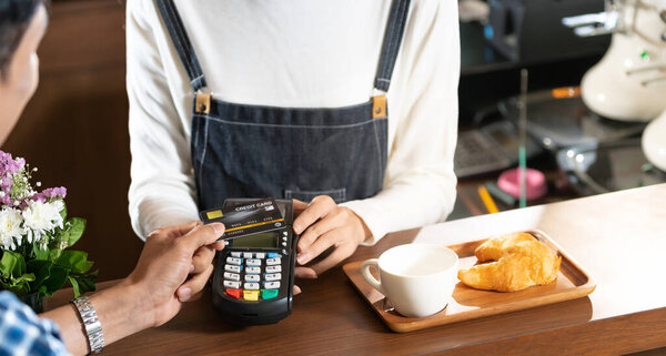 Asian customer using contact-less credit card nfs technology pay to barista at cafe bar. Contact-less payment preventing from corona-virus covid-19 Spreading and infection, Panoramic web banner crop.