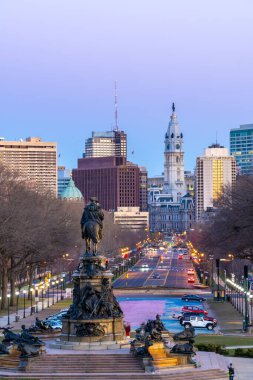 Philadelphia City of City with City Hall Clock Tower ve ABD 'nin Pennsylvania şehrindeki Benjamin Franklin Parkway yolu boyunca uzanan oval parktaki heykel heykeli. Gün batımı