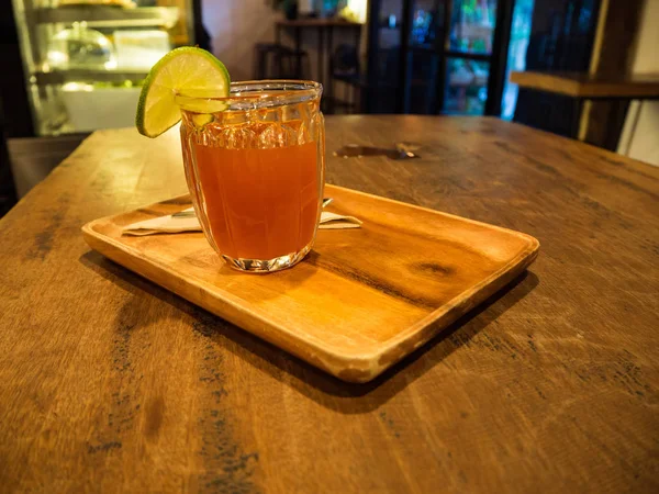 Горячий лимонный чай с ломтиком лимона поверх стакана с медом на деревянном столе — стоковое фото