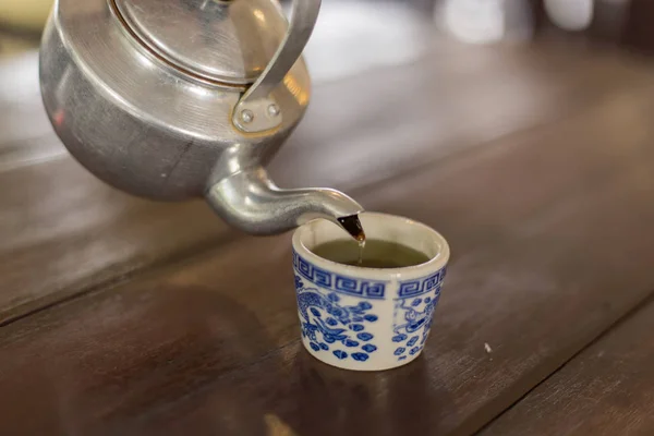 Teekanne gießt Tee in eine Tasse — Stockfoto