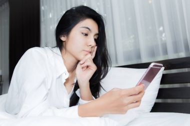 Kadın parlak yatak odasında bir kısa mesaj okuma