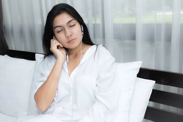 Жінка з навушниками розслабляється на ліжку — стокове фото