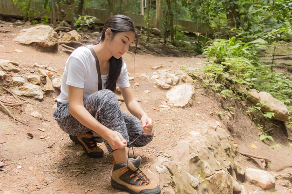Asyalı kadın ormanda ayakkabısını bağlamak