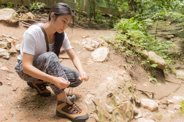 Asyalı kadın ormanda ayakkabısını bağlamak