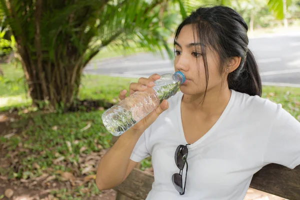 Woman drinks water from bottle in the park