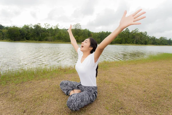 Jovem mulher asiática desfrutando e relaxando na grama verde — Fotografia de Stock